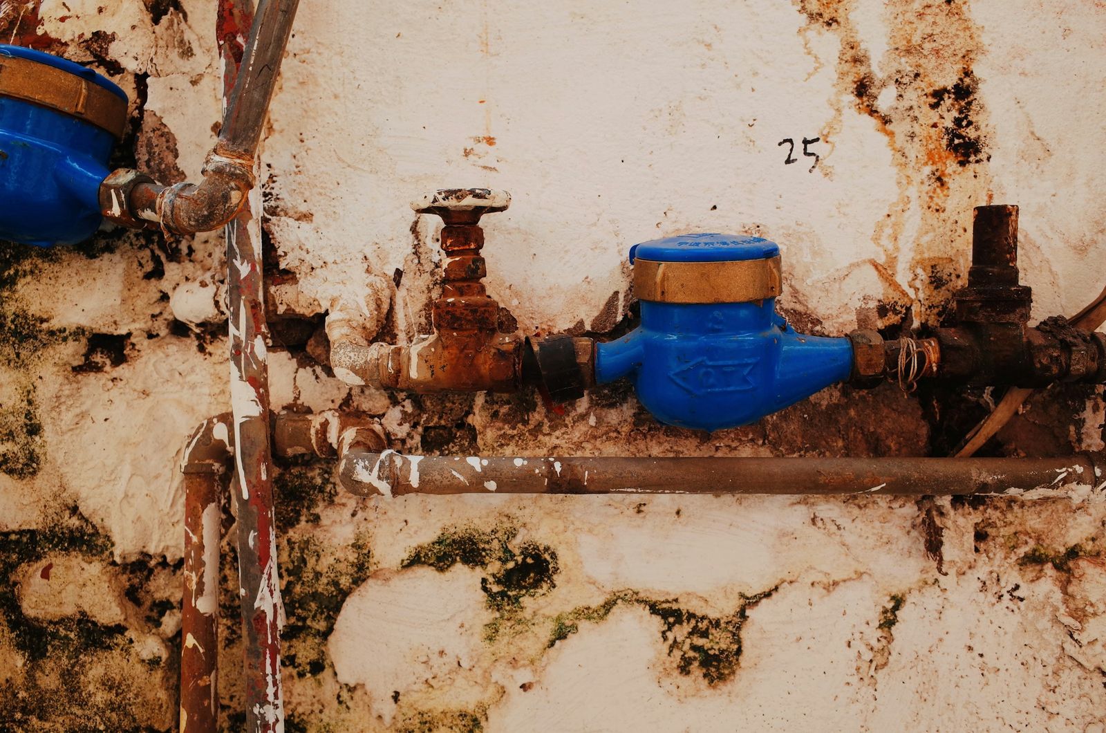 Canalisations corrodées et compteur d'eau sur un mur rongé par l'humidité