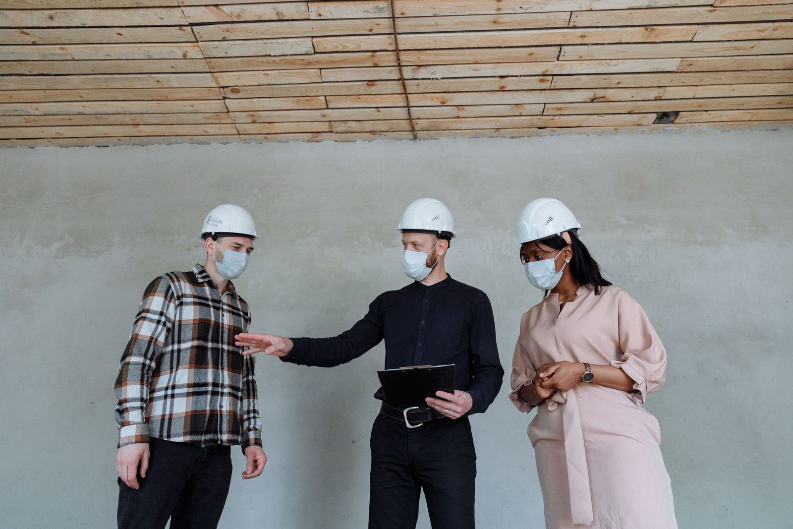 Chef de chantier présentant le planning de travaux à deux clients dans un logement en rénovation