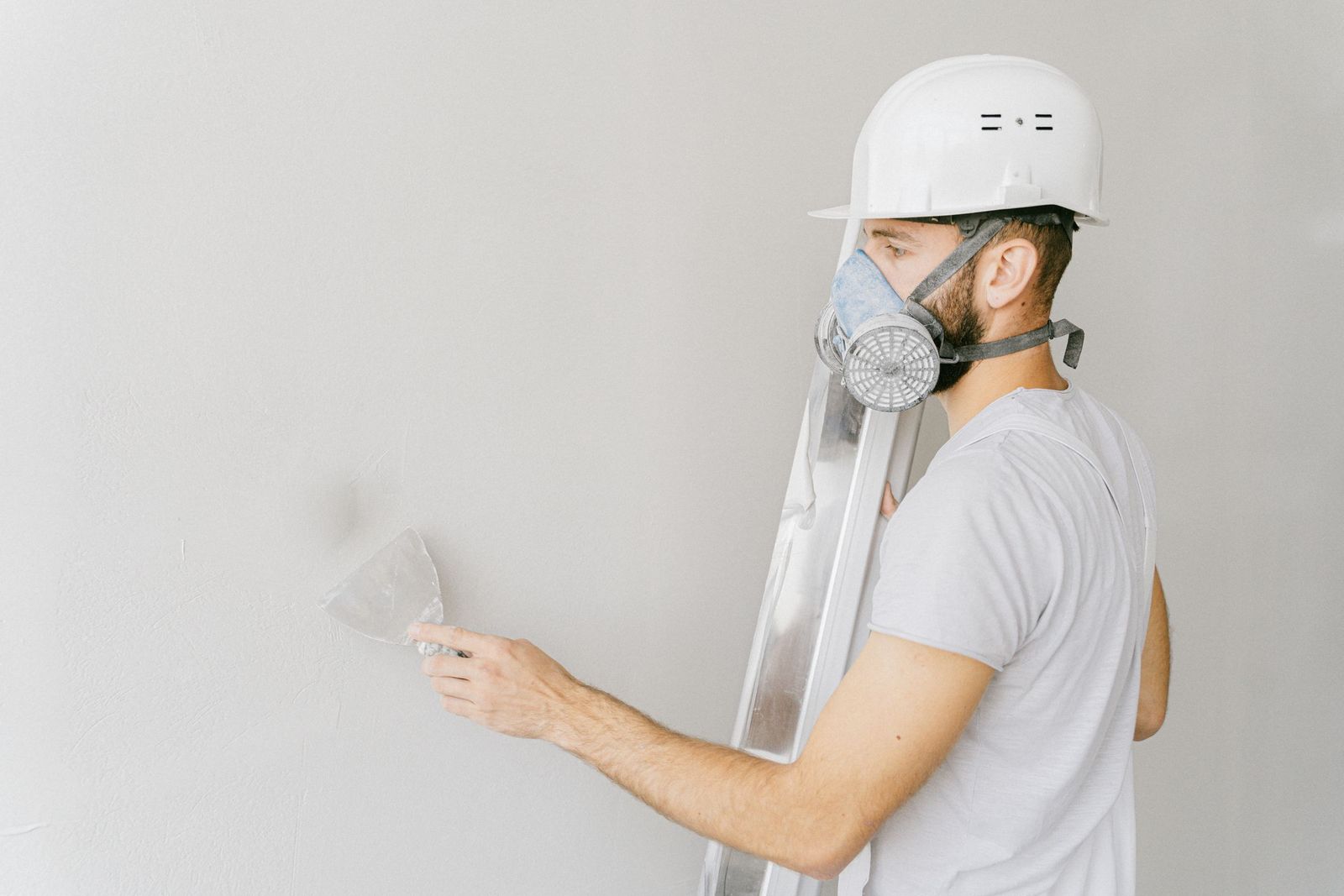 Ouvrier masqué lissant l'enduit d'un mur