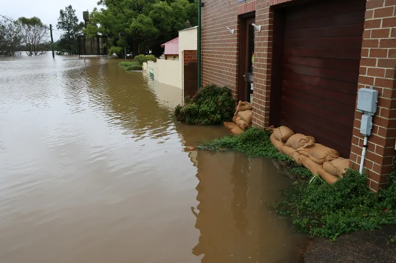Sacs de sable empilés devant l'entrée d'un bâtiment en briques pendant une crue