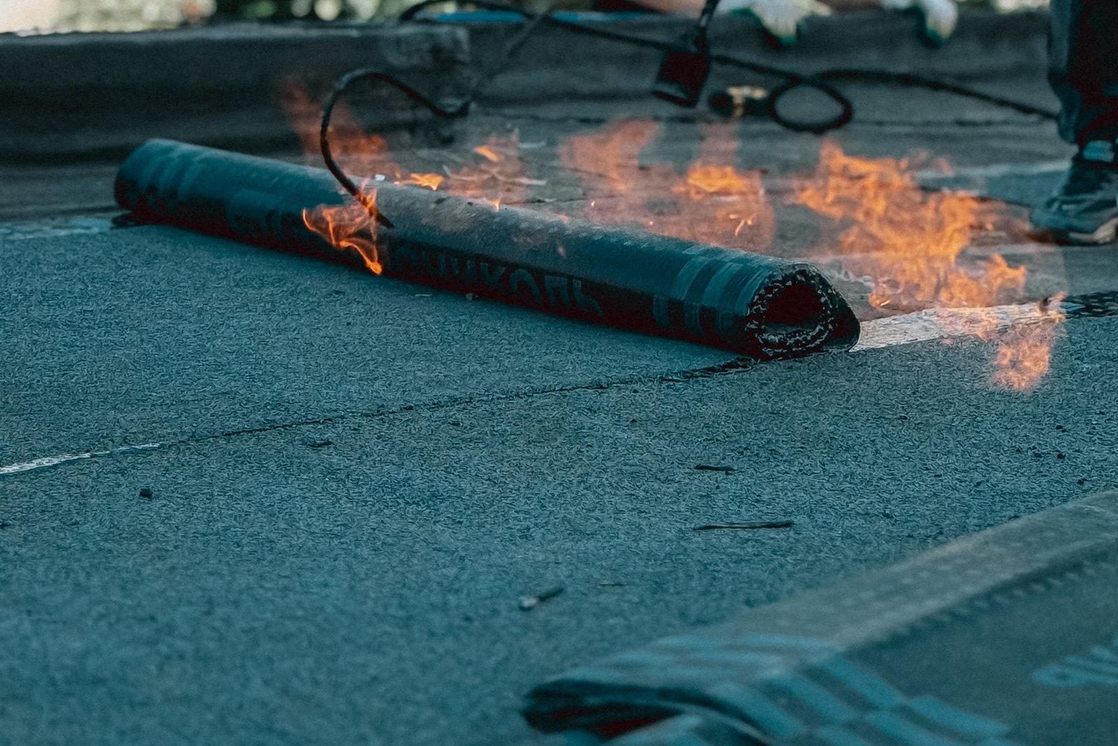 Pose au chalumeau d'un rouleau de membrane d'étanchéité bitumineuse sur une toiture-terrasse